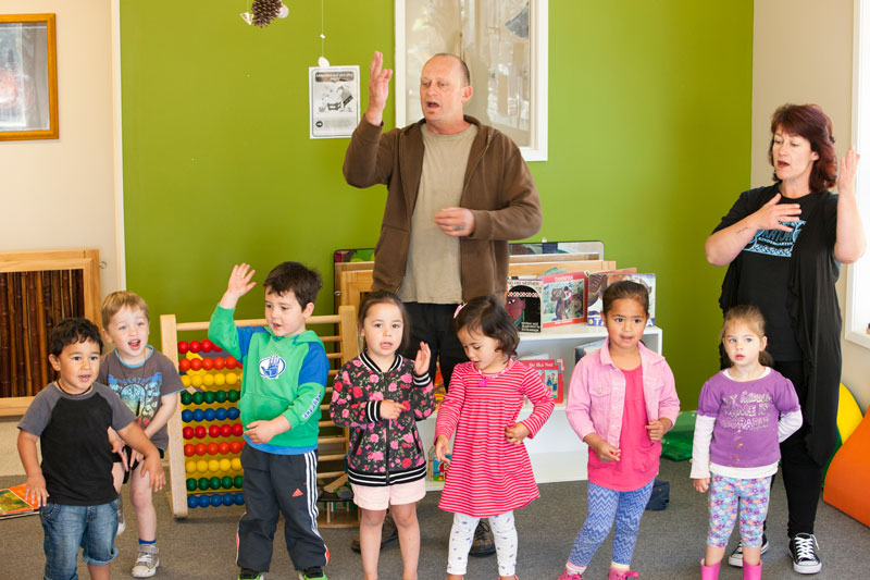 A group of tamariki and kaiako singing and doing actions to a waiata