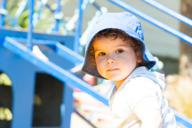 Toddler standing by play equipment