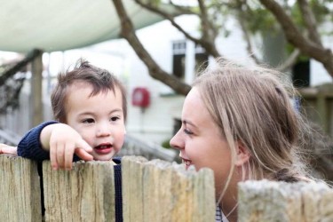 Kaiako and child looking over a fence. 