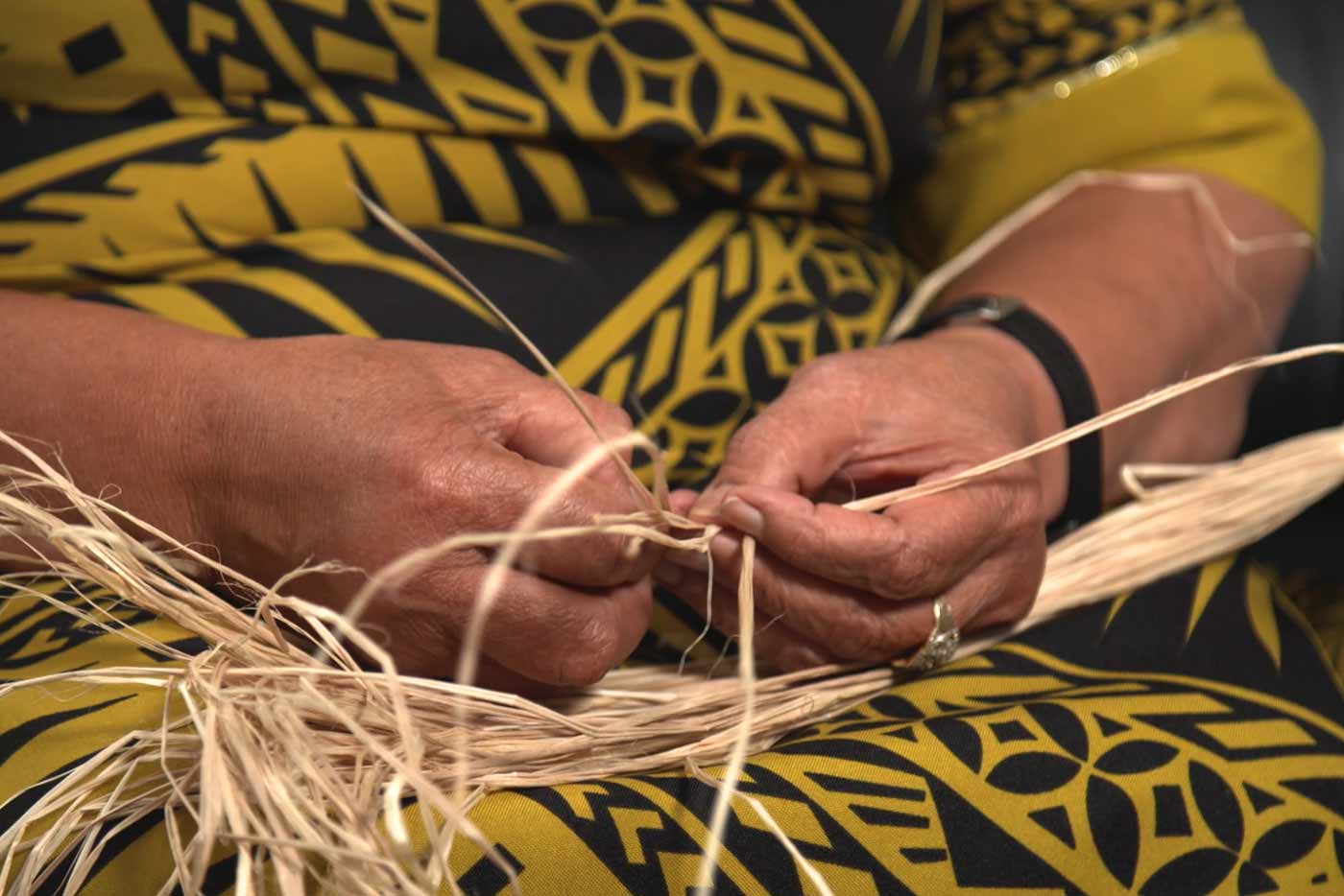 Grandmother's hands weaving on her lap.