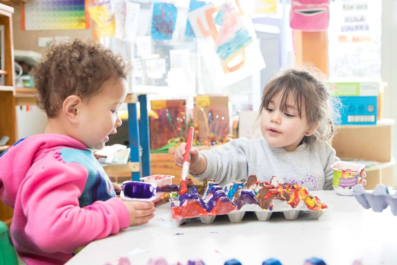 Two children painting an egg box. 