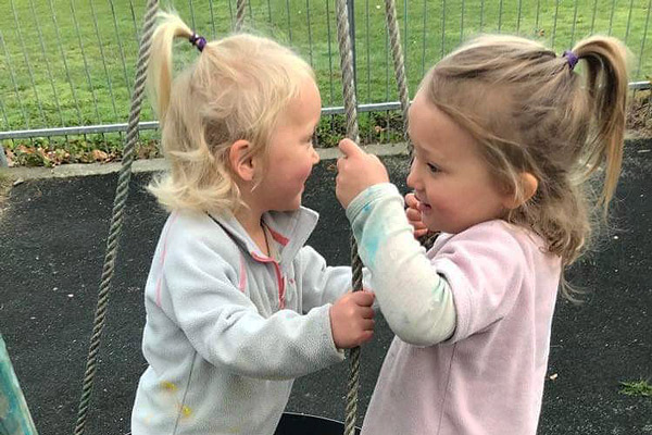 Twins Eliza (on the left) and Amber playing on a swing together