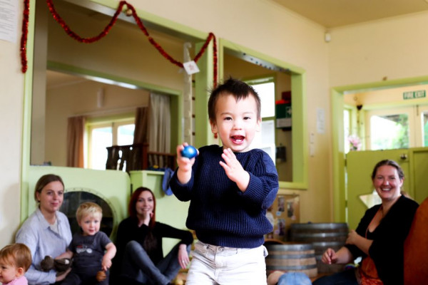 A child with a toy standing in the middle of a circle smiling.