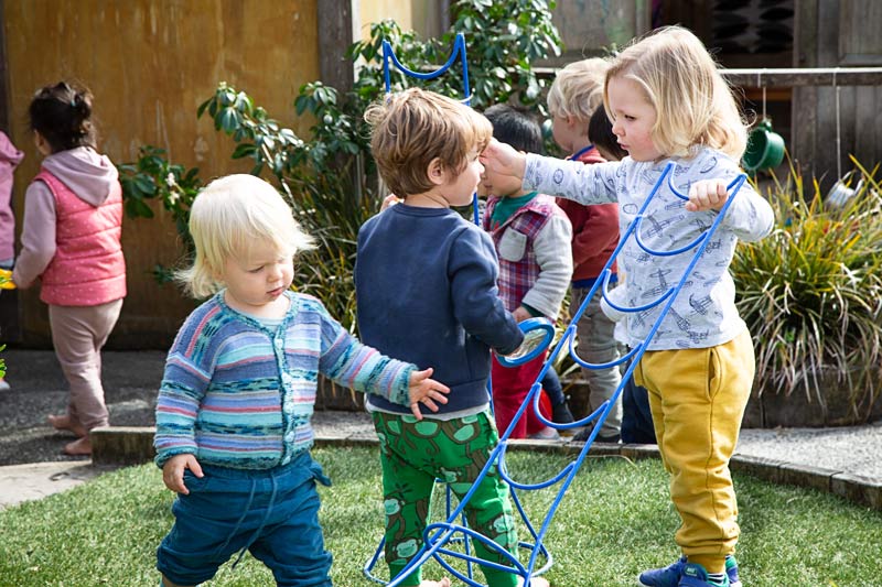 Two tamariki talk while working out how to build something outside.