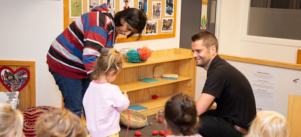 Father with child and kaiako in play area. 